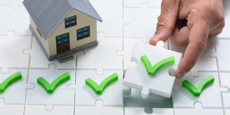 A,Person's,Hand,Solving,Check,Mark,Puzzle,Near,House,Model